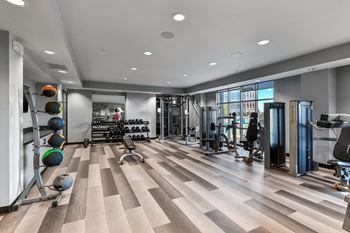 A gym with a variety of equipment and a wooden floor.